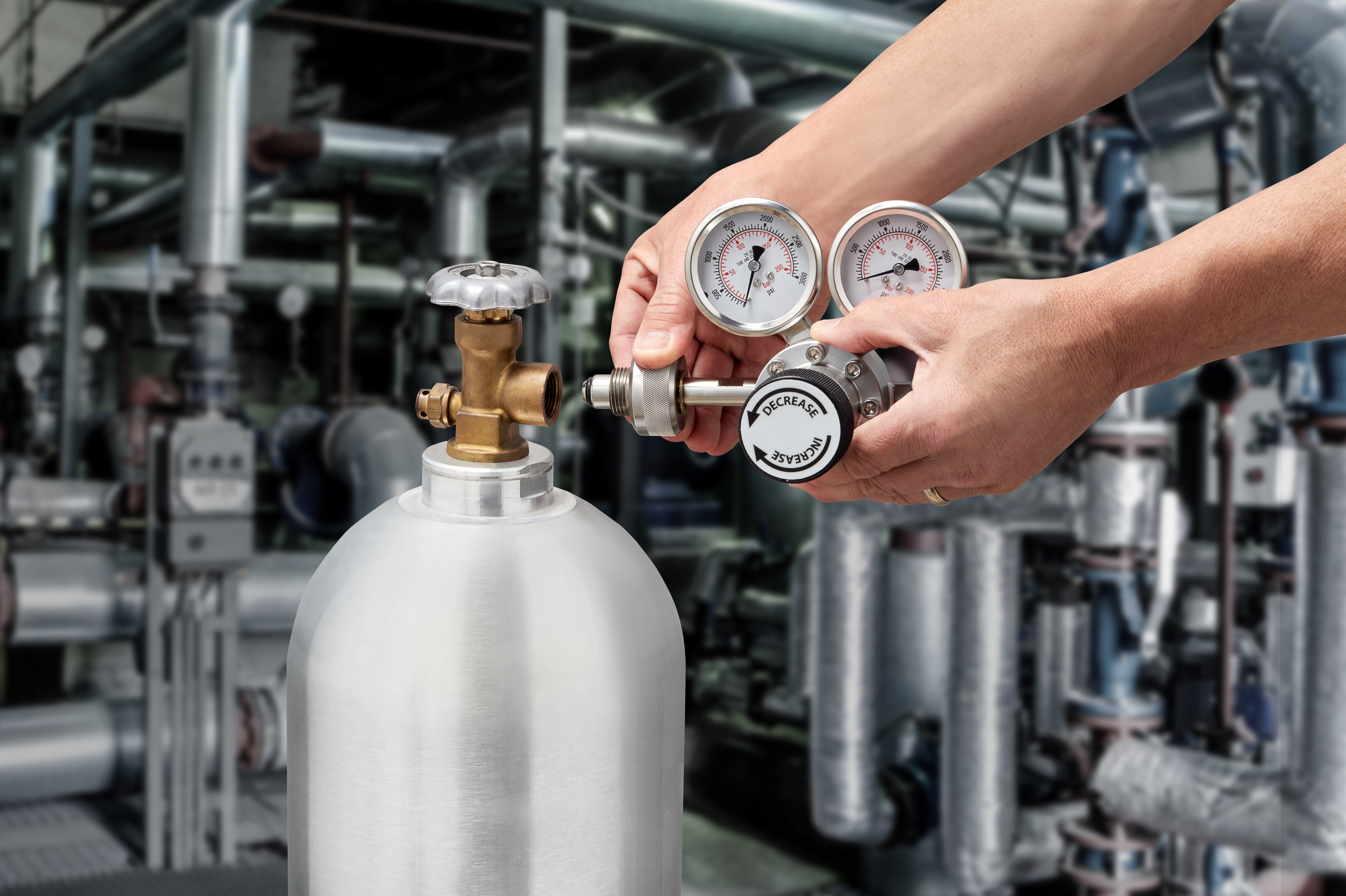 Technician connecting a pressure regulator to a CGA 580 gas cylinder using a Ralston Quick-test adapter