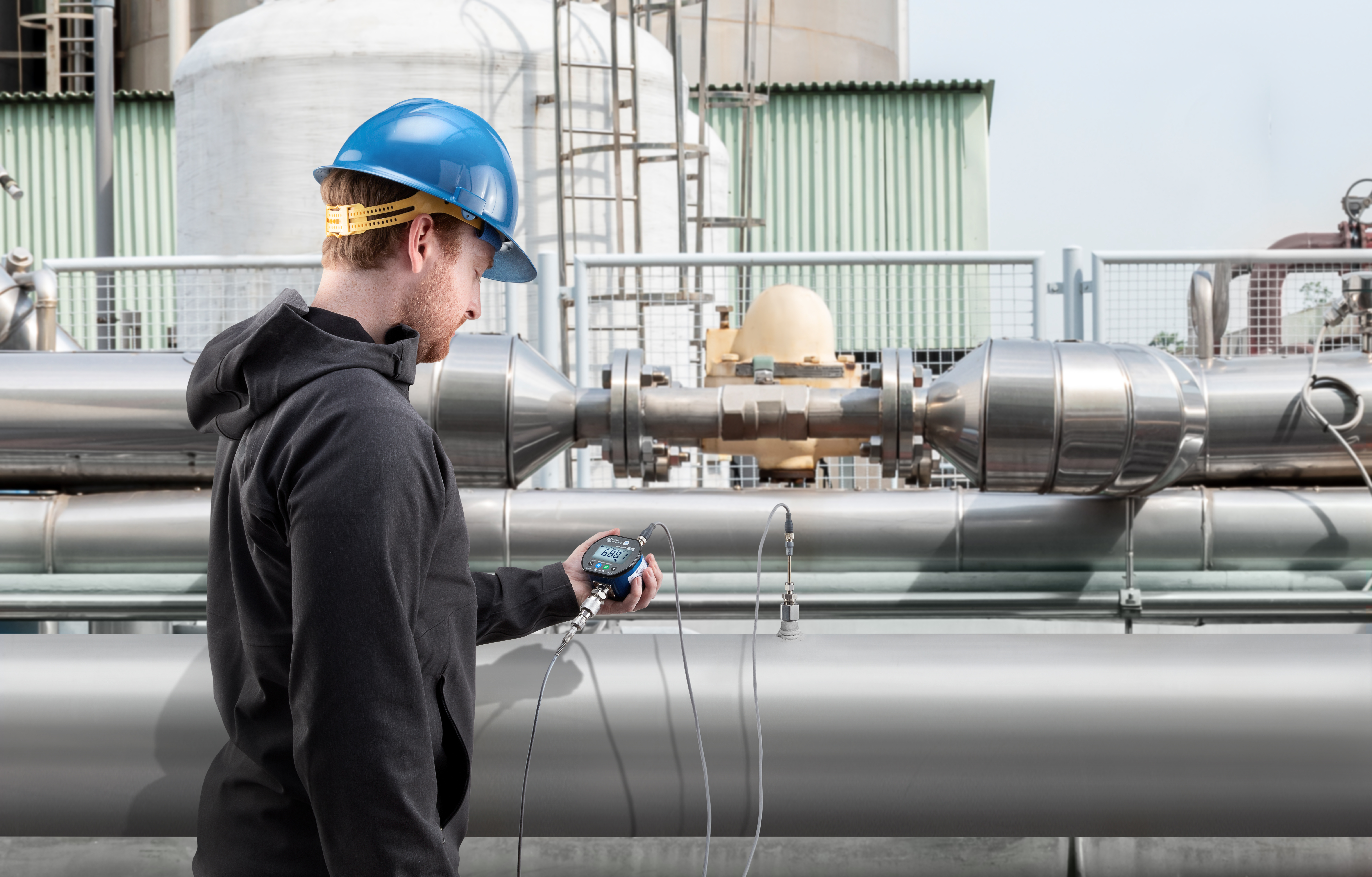 A technician using a Ralston Field Gauge LC20 to calibrate pressure on an industrial piping system