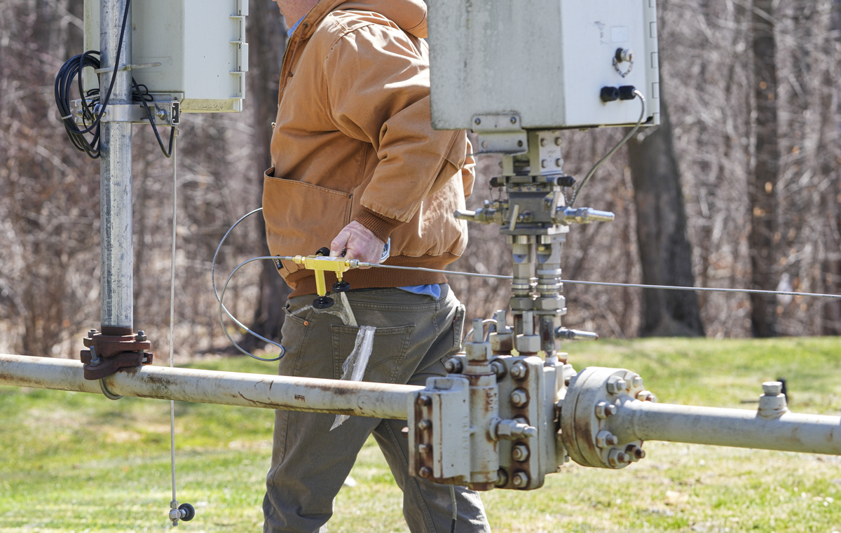 Technician carrying the end of the hose to the test site while the QTHR Hose Reel remains mounted on the truck.