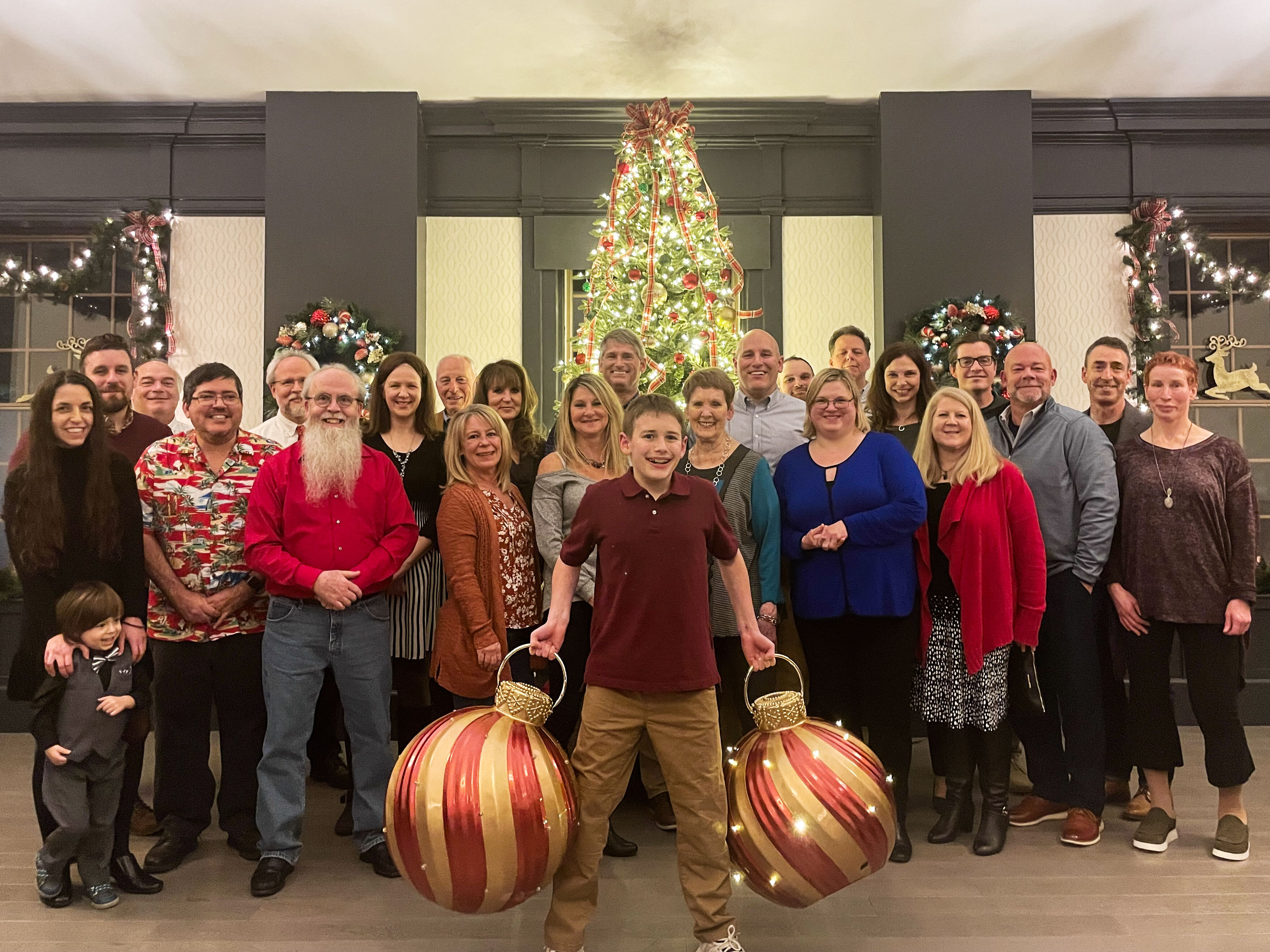 Group of Ralston team members dressed in holiday attire, smiling at a restaurant during the annual Christmas party.