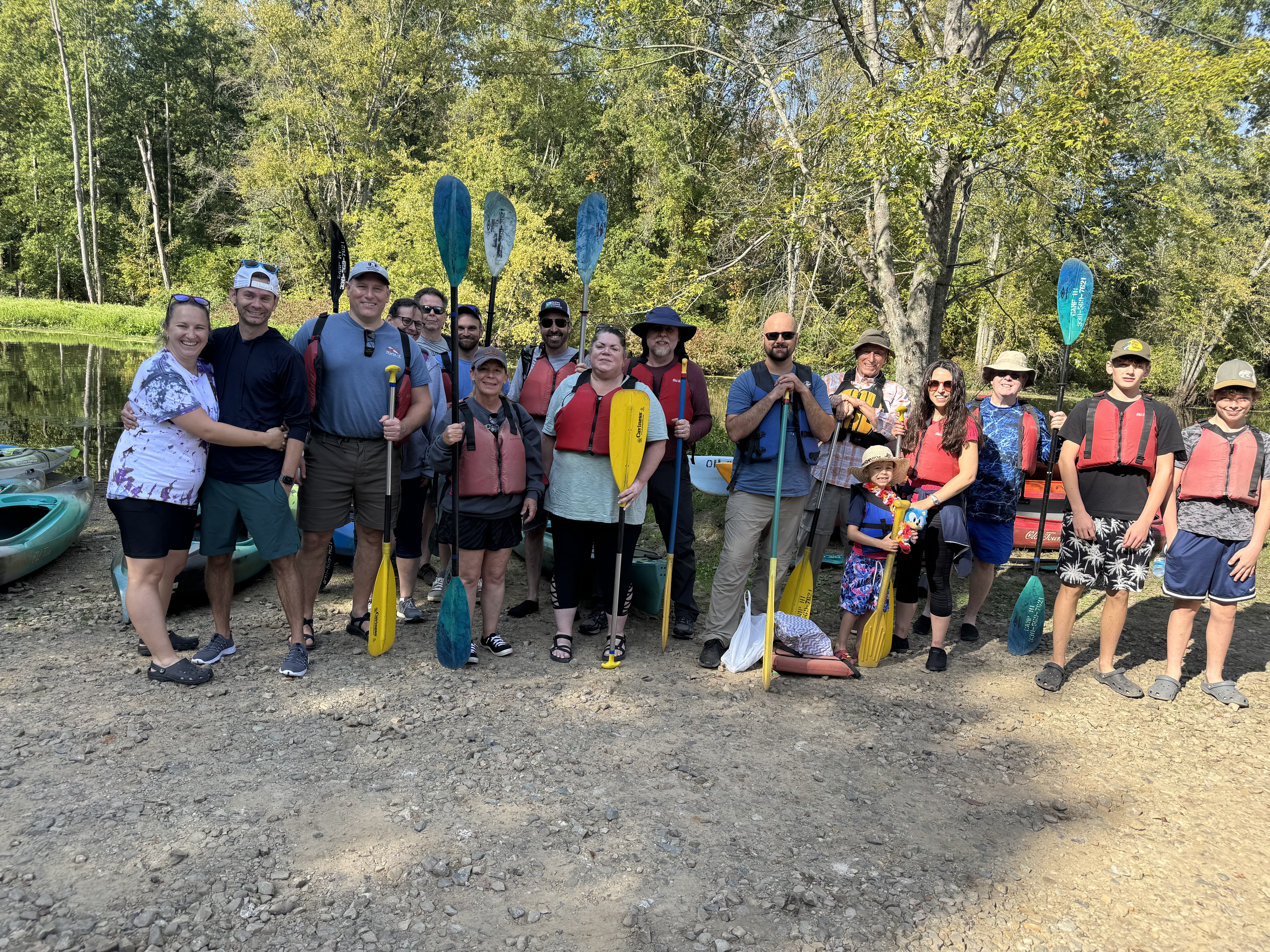Group of Ralston employees and guests holding paddles and wearing life jackets before a group kayaking trip.