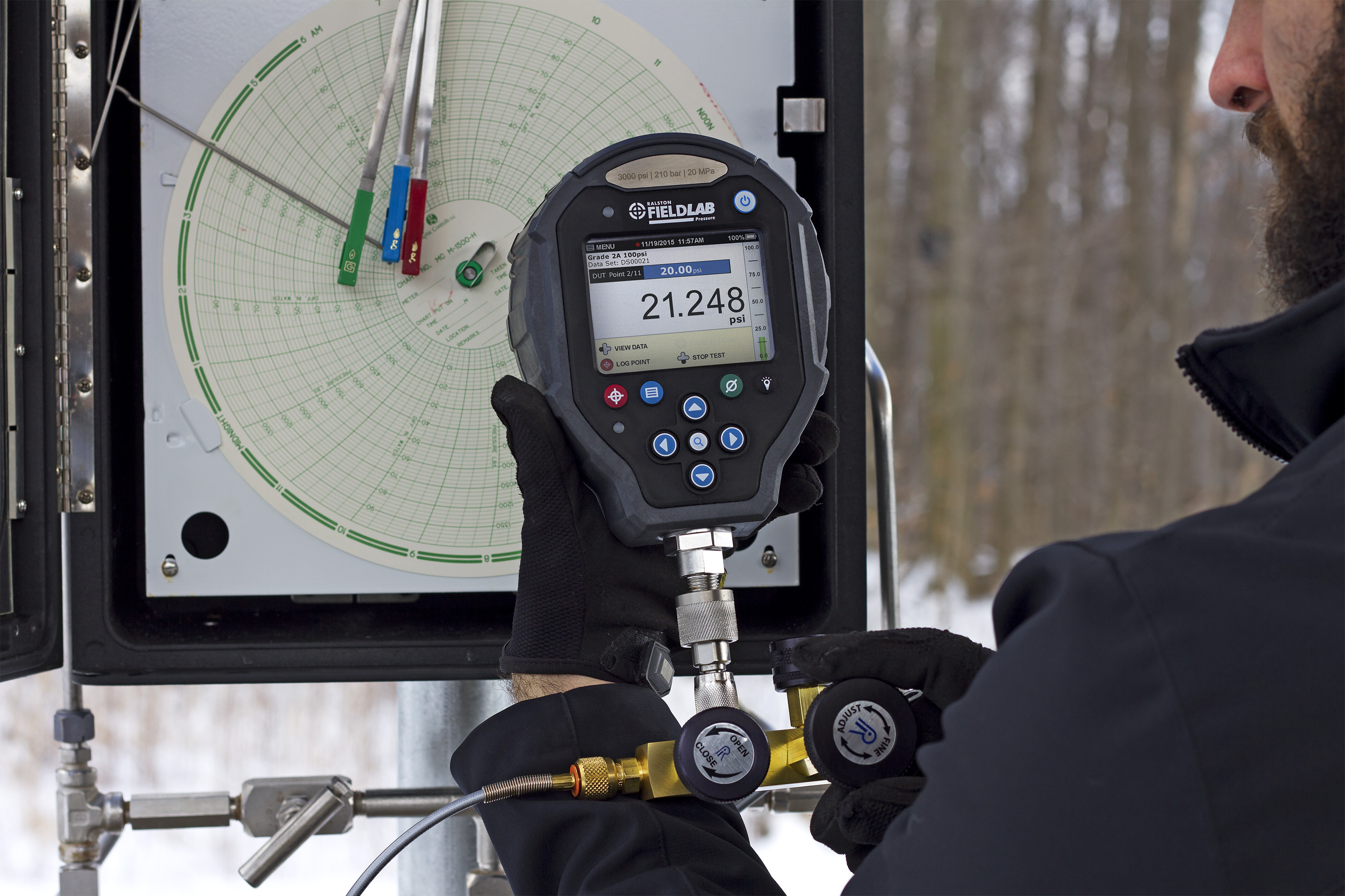Technician using a Ralston FieldLab pressure calibrator to verify chart recorder pressure on a natural gas pipeline.