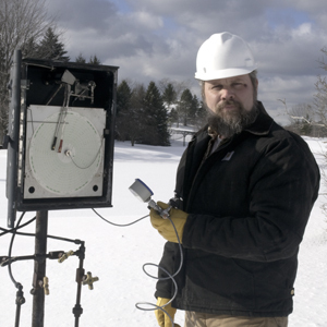 Pipeline technician preparing to calibrate a chart recorder on a natural gas pipeline during winter conditions.