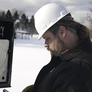 Technician using a nitrogen calibration setup to verify chart recorder pressure on a natural gas pipeline.