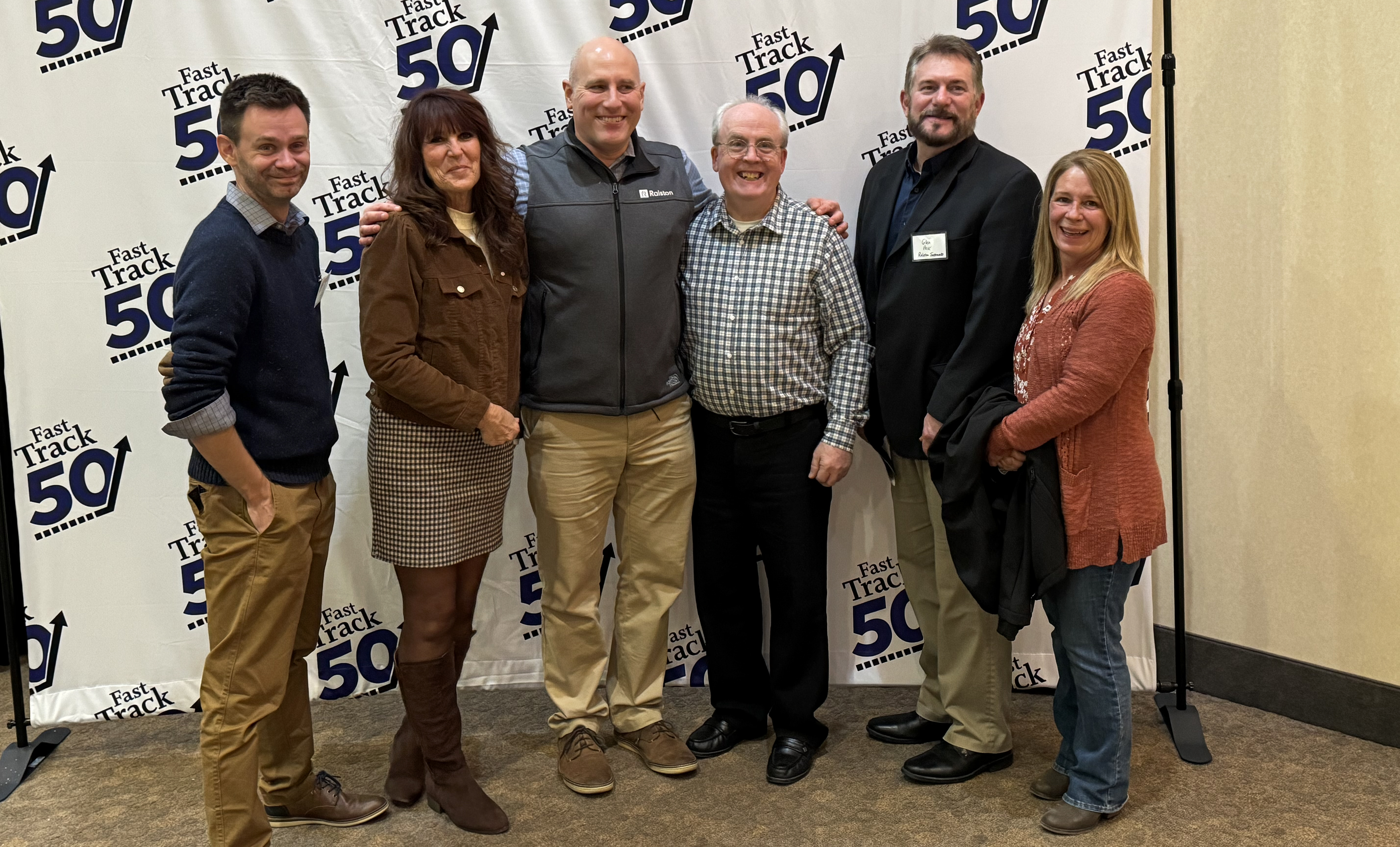 Ralston Instruments team stands together in front of the Fast Track 50 award event backdrop.