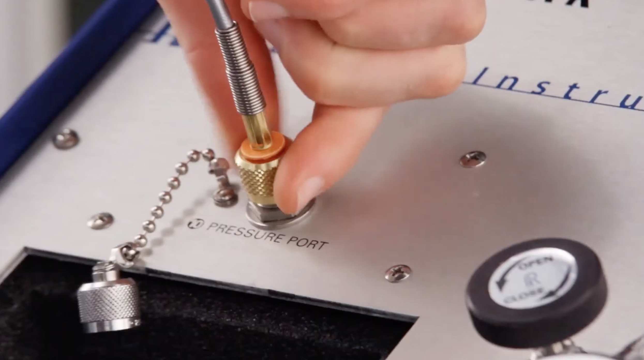 Close-up of a technician connecting a Quick-test hose to the pressure port on the Ralston NitroPak Pressure Source.